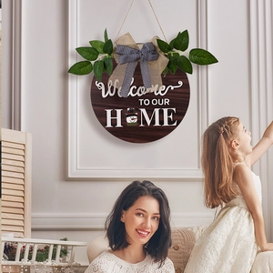 Detail of wooden welcome wreath with rustic burlap bow and green leaves on white wall