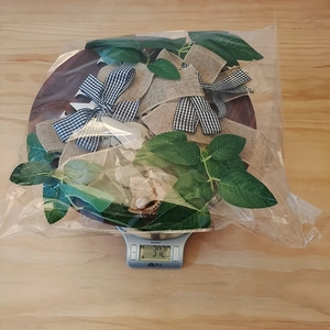 Weight measurement of rustic welcome wreath with green leaves and plaid bow in packaging