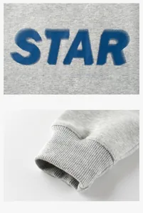 Détail du sweat gris enfant montrant l'imprimé étoile bleue et les poignets côtelés