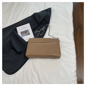 Close-up of a light brown flap clutch bag with silver chain on a stylish set