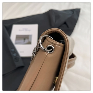 Detail of a brown leather envelope bag featuring silver hardware and fine stitching