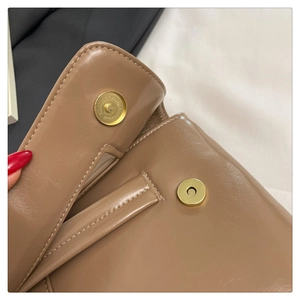 Macro view of brown leather handbag featuring a secure gold magnetic snap closure