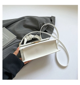 Detail view showing white quilted crossbody bag bottom and gold metal turn-lock closure