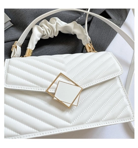 Close-up of white quilted leather handbag with V-shaped stitching and golden square lock
