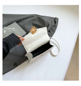 Detailed interior of a white quilted crossbody bag with golden metal magnetic clasp