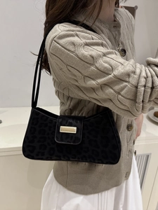 Vintage Umhängetasche mit Leopardenmuster und Goldschließe am Modell mit Strickjacke