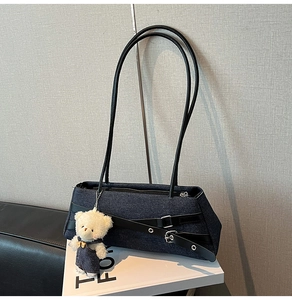 Detail of dark blue denim shoulder bag featuring black leather straps and silver buckles