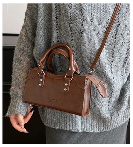 Detail view of retro brown PU leather crossbody bag worn with a knit sweater
