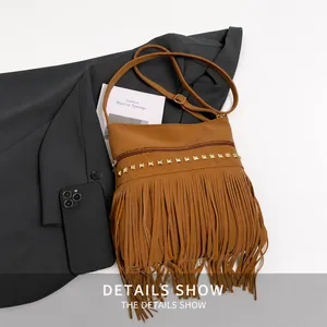Detail of brown PU leather crossbody bag with gold studs, fringe tassels and long strap