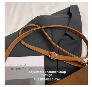 Detail of adjustable brown faux leather shoulder strap with gold buckle and stitching