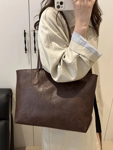 Borsa tote vintage in pelle marrone scuro indossata da modella con cappotto beige