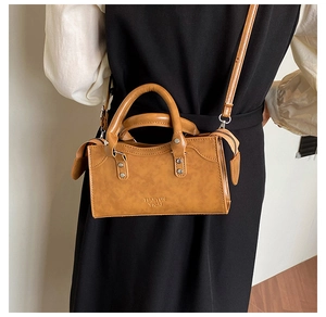Caramel textured small square bag shown on model with top handle and crossbody strap