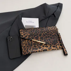 Dettaglio della pochette leopardata con barra di metallo dorata e cinturino da polso