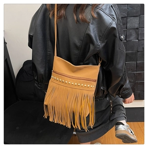 Detail view of camel fringe shoulder bag with gold square studs and zipper closure