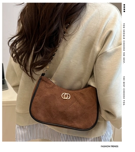 Detail of brown suede crescent bag featuring quilted texture and gold double-ring hardware