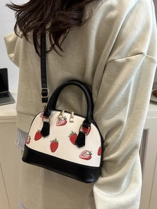 Borsa a mano bianca con stampa di fragole e manici neri indossata da una modella