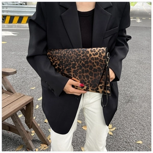 Detail of leopard print clutch featuring gold metal trim and black leather wrist strap