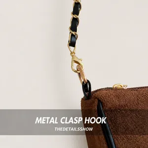 Detailed close-up of the vintage brown suede bag with golden metal hooks and chain strap
