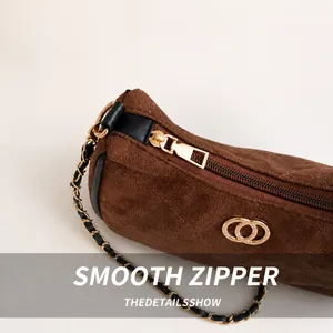 Detail of gold metal zipper and interlocking logo on brown suede shoulder bag