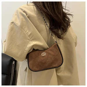 Detail of dark brown suede shoulder bag with quilted stitching and gold chain strap