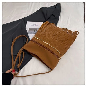 Detail of caramel brown tassel shoulder bag with golden studs and zipper closure