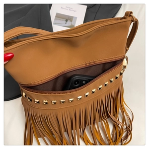 Detailed view of brown tassel tote bag with gold studs and a phone inside for scale