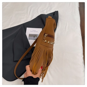 Detailed view of a brown leather crossbody bag with long fringes and metal rivet accents