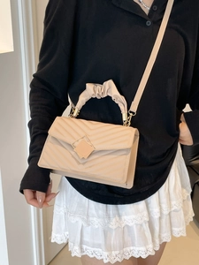 Chic cream quilted crossbody bag with pleated handle and V-pattern stitching on model
