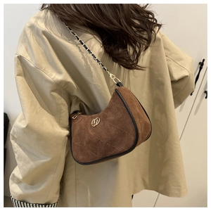 Detail of dark brown suede hobo bag featuring quilted pattern and gold ring buckle