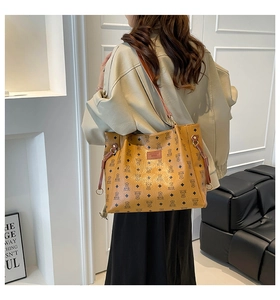 Detail of yellow tote bag with bear pattern and chain strap on a model shoulder