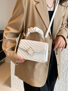 Quilted white crossbody bag with gold hardware and ruched handle on elegant model