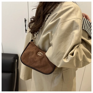 Detailed view of brown suede shoulder bag featuring quilted stitching and golden hardware