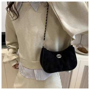 Detail of black PU leather shoulder bag with gold hardware worn over a beige hoodie