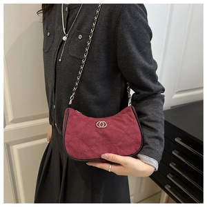 Detail of burgundy suede-texture crossbody bag with rhombus pattern and gold chain strap