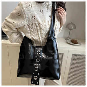 Detail of a shiny black faux leather hobo bag featuring silver punk metal eyelets