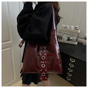 Detail of burgundy patent leather tote with metallic eyelets and silver studs