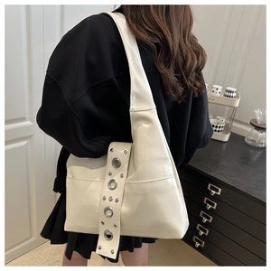 Detail of cream white shoulder bag featuring large silver metal eyelets and soft PU leather