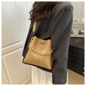 Litchi texture khaki bucket bag with decorative cream chain on female model