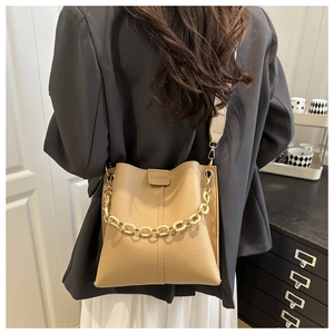 Detail of beige bucket bag featuring chunky chain decor and stylish textured leather