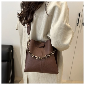 Detail of dark brown leather bucket bag with fashion label and textured chain strap