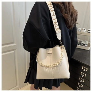 Chic beige bucket bag with wide letter strap and white chunky chain detail shown on model