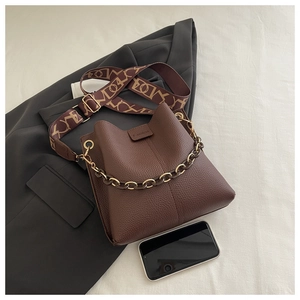 Close-up of brown litchi pattern leather bucket bag with fashion stamp and gold chain