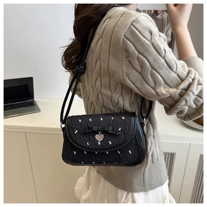 Detail of black heart pendant and bow on quilted shoulder bag with rabbit embroidery