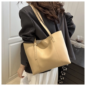 Borsa tote beige in ecopelle con fibbie laterali indossata da una modella donna