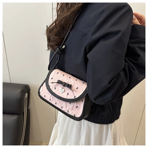 Nahaufnahme der rosa Plissee-Handtasche mit schwarzer Schleife und silbernem Herz-Anhänger