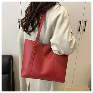Detail showing red tote bag with adjustable strap and embossed fashion text
