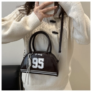 Detail of dark brown crescent bag featuring Los Angeles print and silver chain accessory
