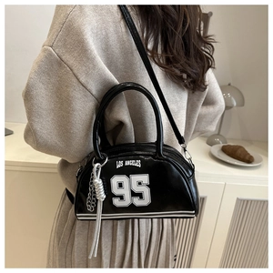 Detail of black patent leather crossbody bag featuring Los Angeles 95 print and silver charm
