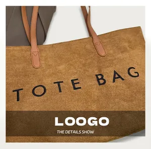 Détail rapproché de la texture en velours côtelé marron et broderie du sac fourre-tout