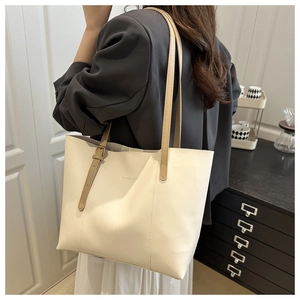 Close-up of the beige leather tote bag featuring brown straps and fashion embossed text
